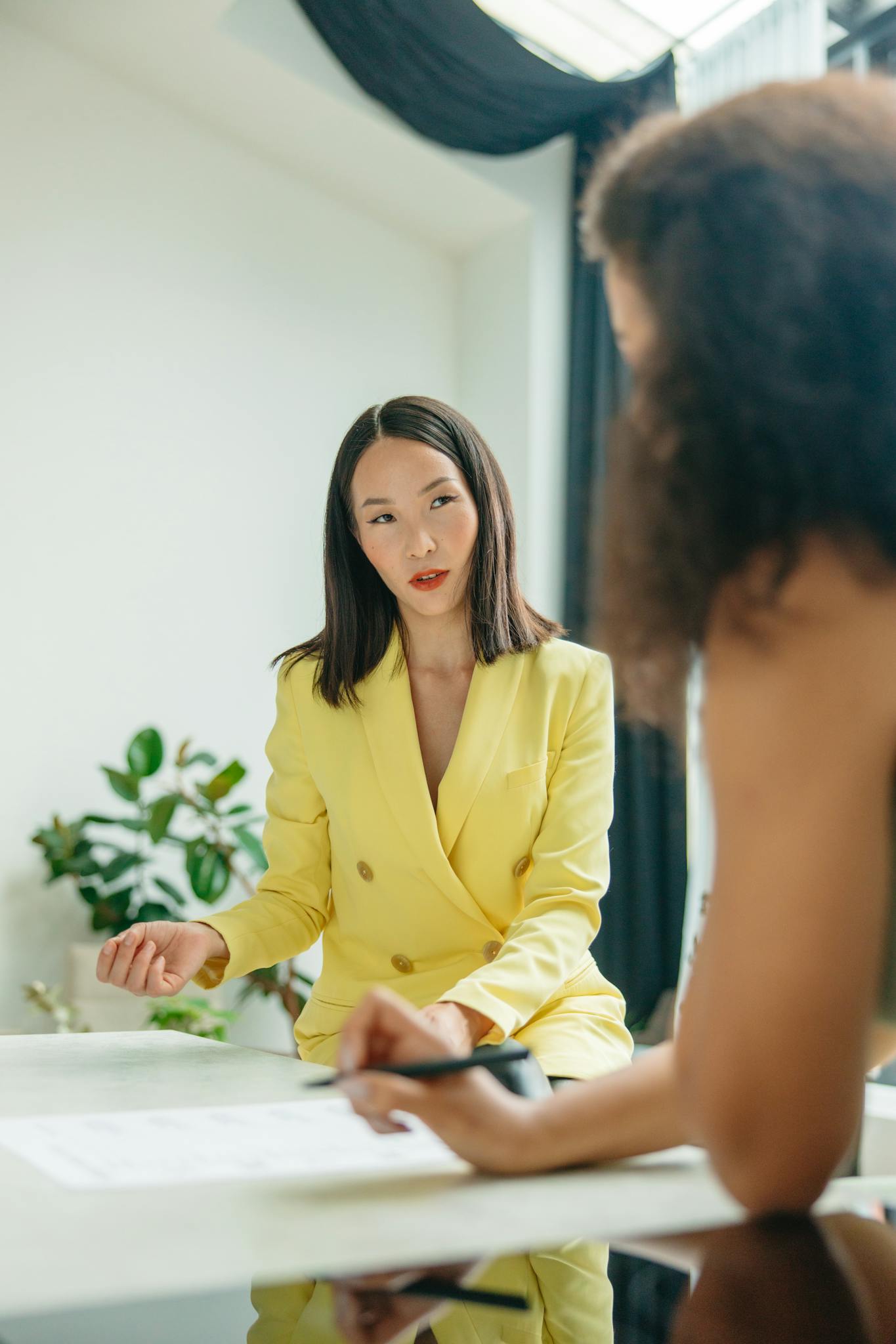 Two women engaged in a lively conversation during a business meeting indoors.